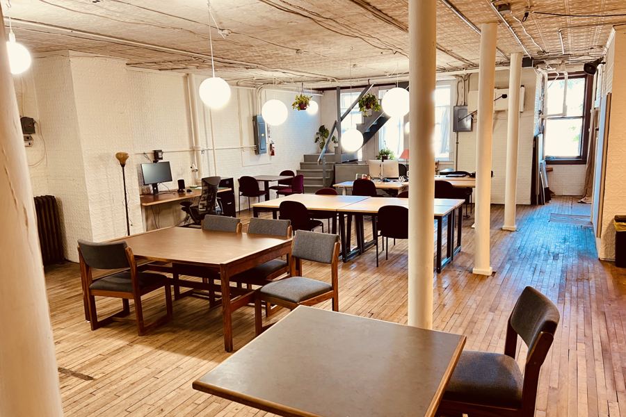 Shared tables and desks along the loft's long wood floor